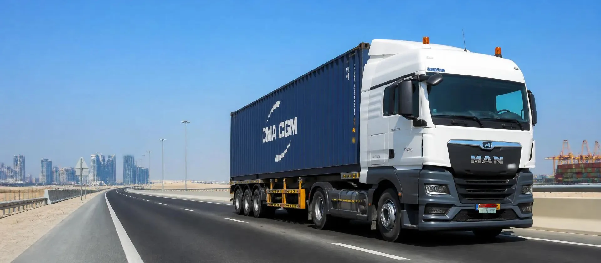 Freight truck carrying a container along a highway in bright daylight